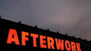 Sarkana neona izkārtne ar uzrakstu Afterwork pretī tumšām vakara debesīm