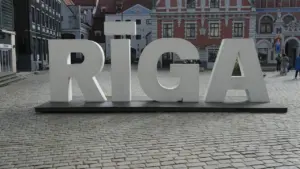 Liels RĪGA uzraksts uz bruģētas ielas vēsturiskā pilsētas centrā Rīgā, Latvijā.