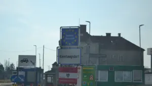 Robežkontroles punkts ar Eiropas Savienības un Austrijas karogiem ceļotājiem.